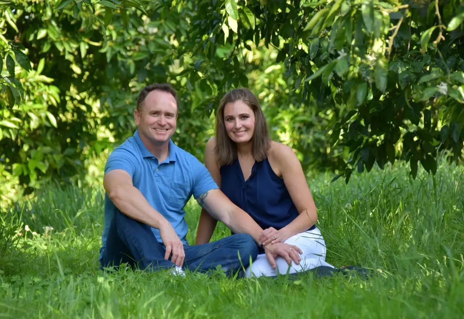 A man and woman sitting in the grass.
