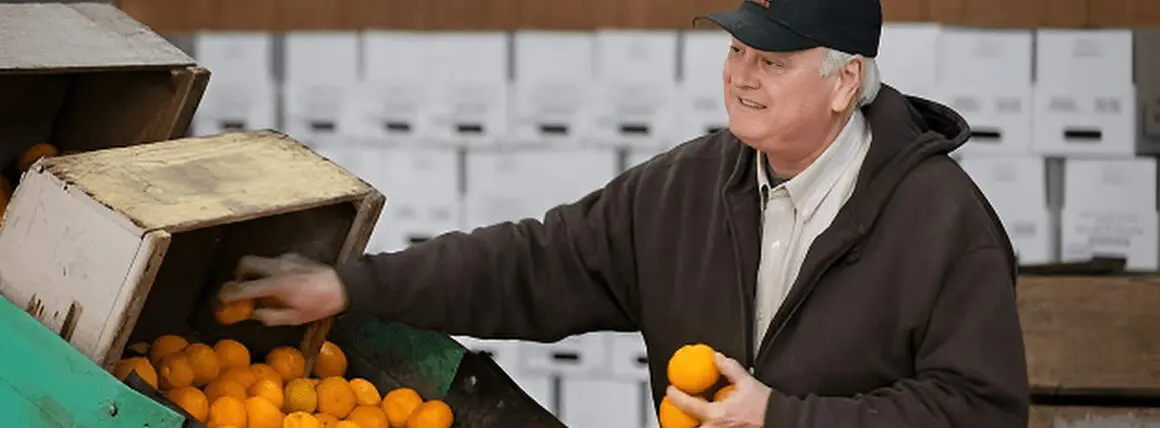 A man holding oranges in his hand and smiling.